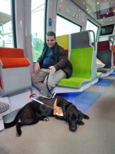 Thémis est allongée devant son bénéficiaire, assis sur un siege coloré du RER